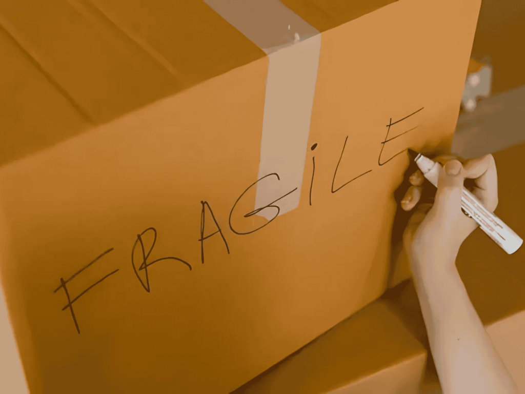 A labeled fragile moving box being packed securely by Clockwork Moving in Weddington, NC.