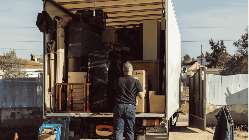 A professional mover unloading furniture and boxes from a truck, representing long-distance moving services provided by Clockwork Moving Company in Charlotte, NC.